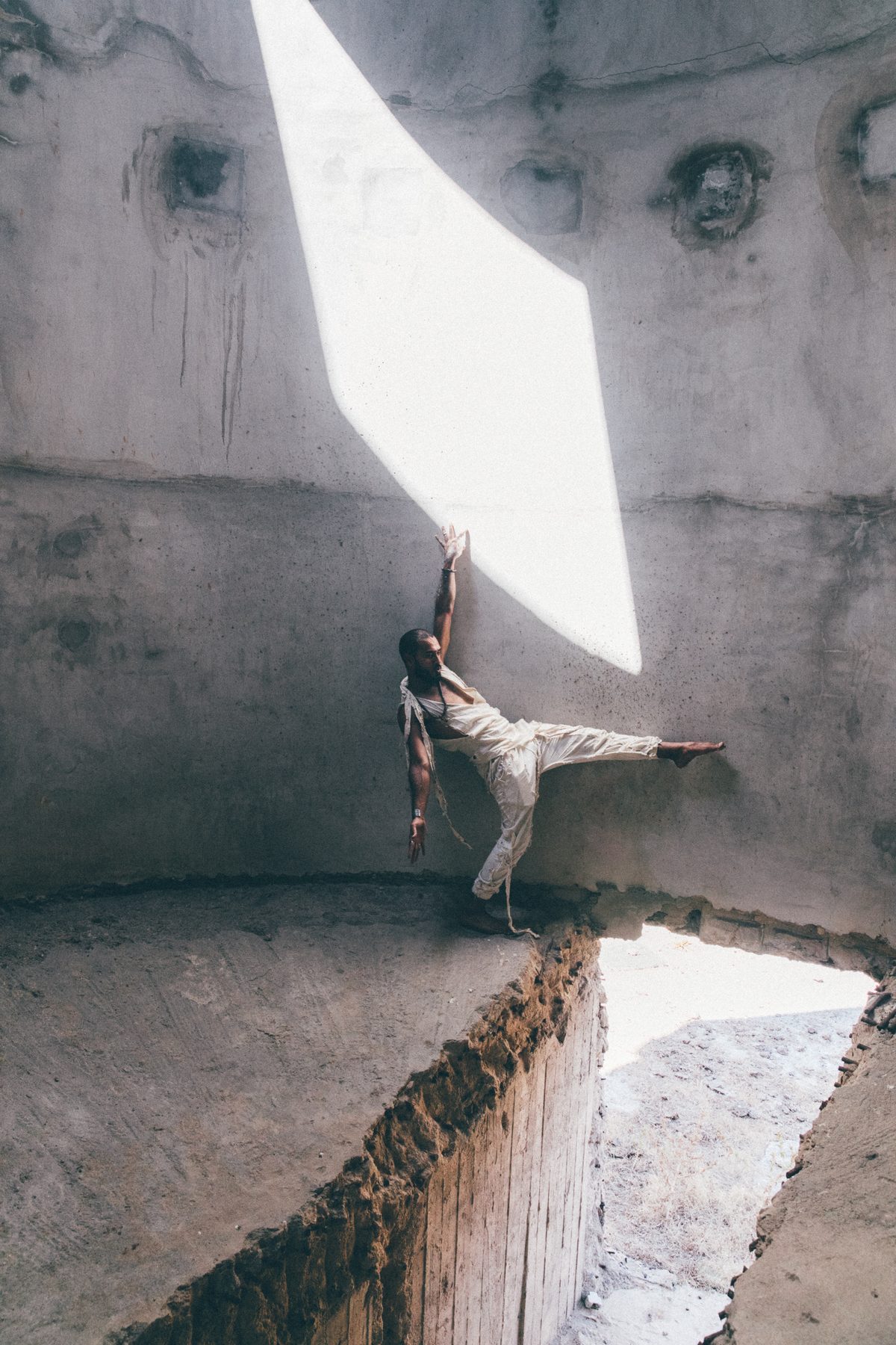 Ali Sardar in a low, weighted crouch beneath a shaft of light